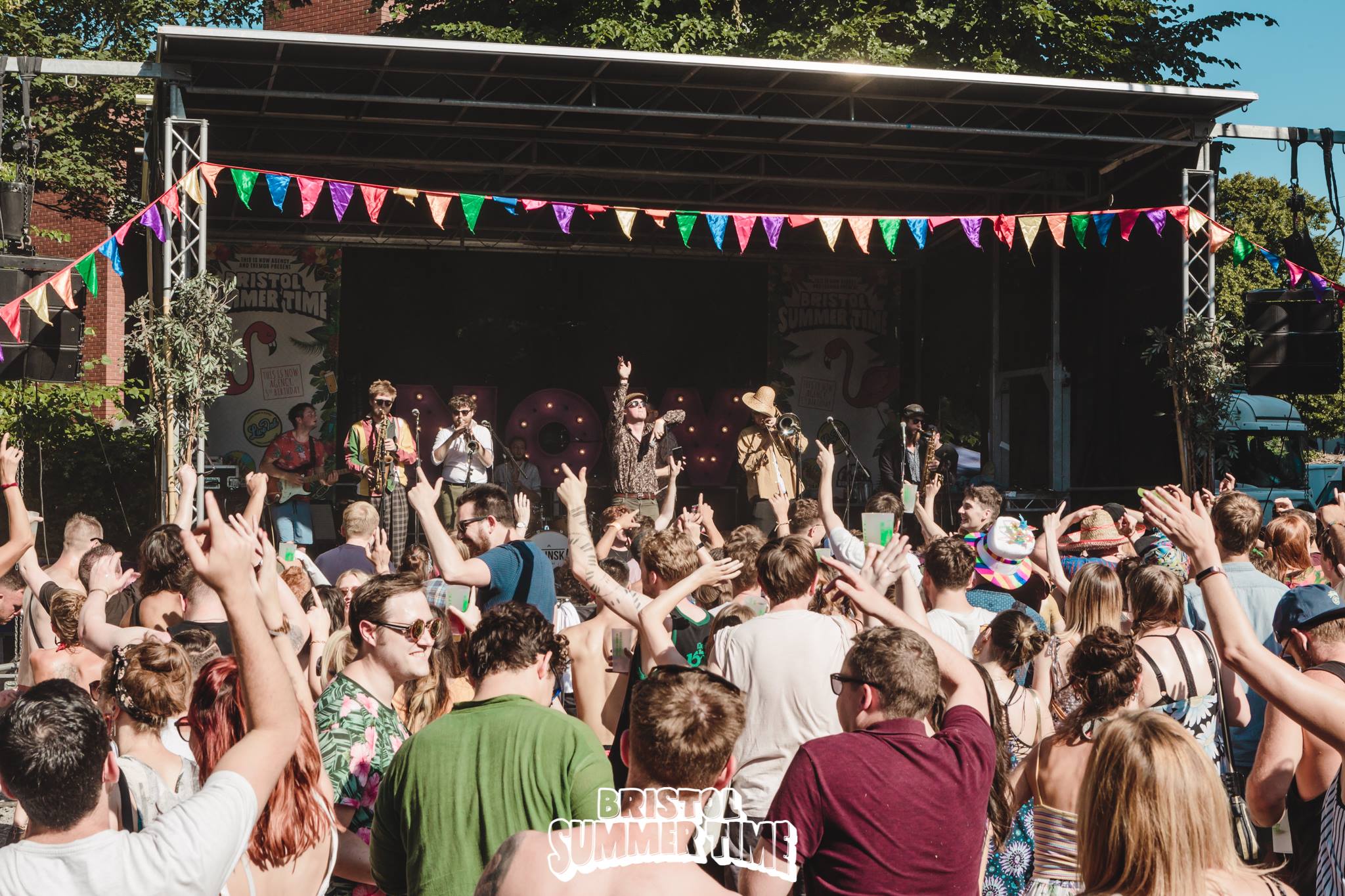 Photo taken by Leora of FarLight Productions - the view over the crowd to the main stage of Bristol Summer Time with Chainska Brassika jumping around on stage