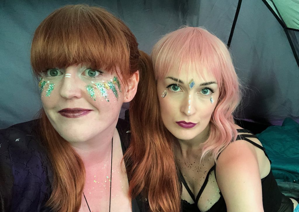 My friend Amanda and I in my tent having just finished our glitter makeup and gems. Amanda is wearing a baby pink fringed wig, and I have my hair in ponytails. Selfie time!