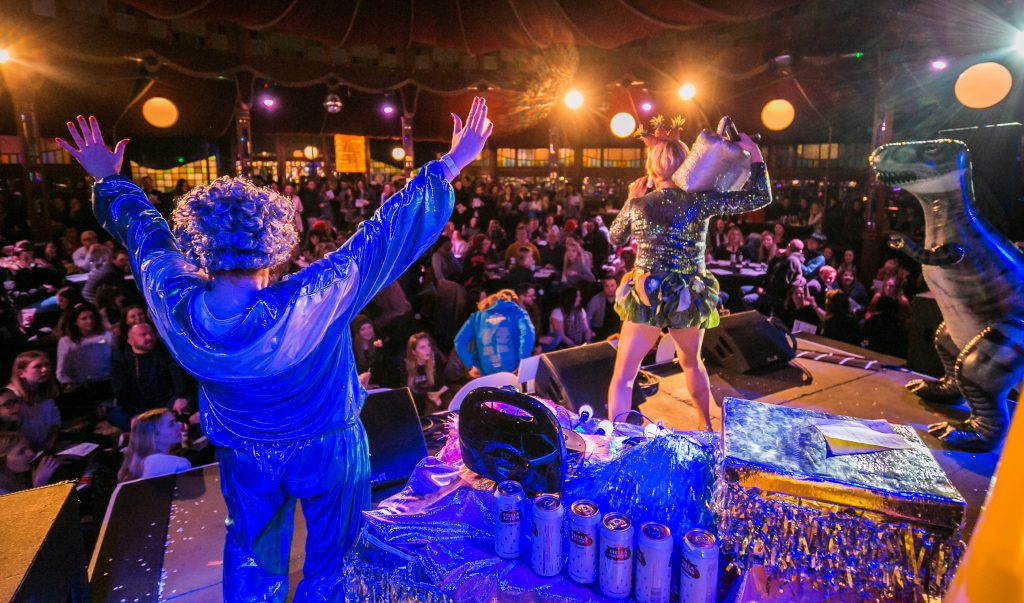 View from the stage out into the crowd in the Spiegeltent, with performers wearing sparkly outfits.